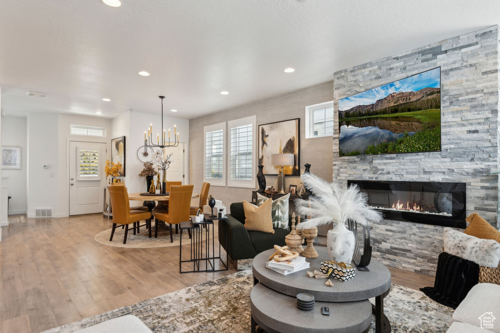 Living area with visible vents, a fireplace, wood finished floors, a chandelier, and recessed lighting
