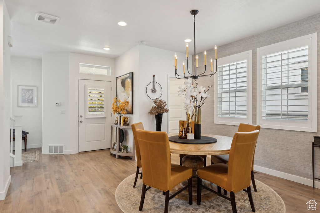 Dining area with a notable chandelier, baseboards, visible vents, and light wood-style flooring