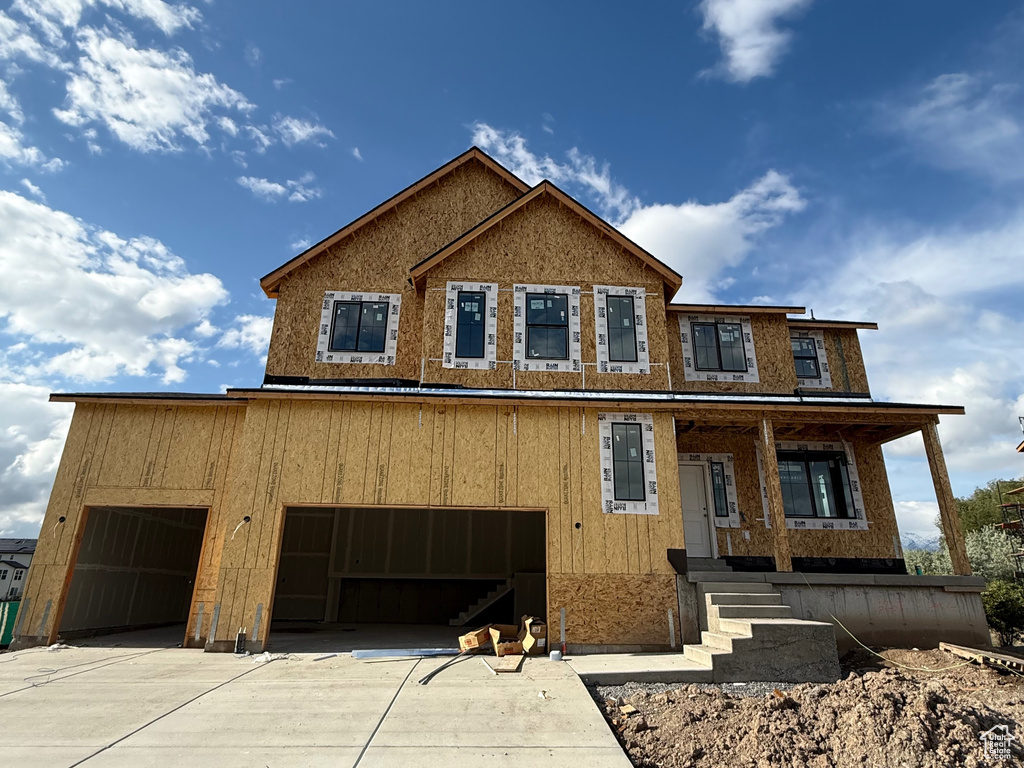 View of front of home with concrete driveway, a porch, and brick siding