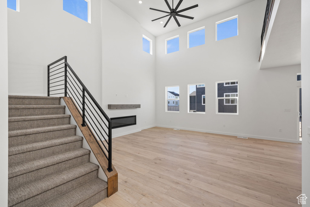 Interior space featuring wood finished floors, baseboards, a glass covered fireplace, a high ceiling, and recessed lighting