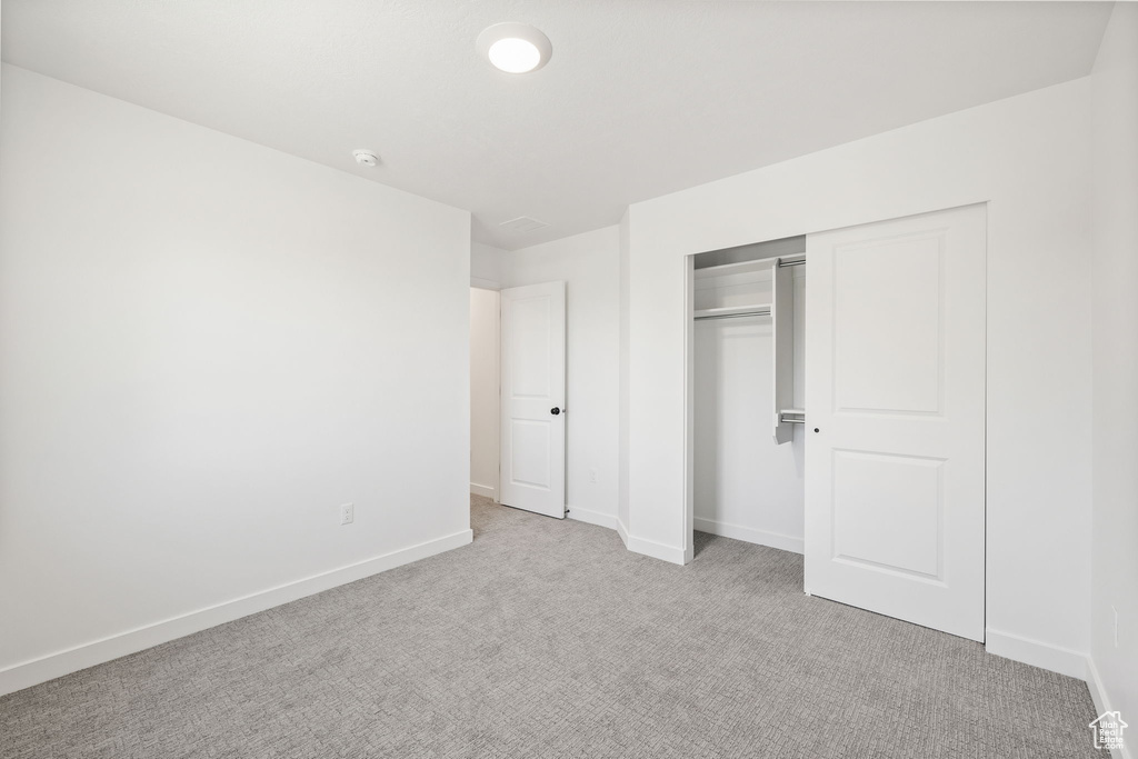 Unfurnished bedroom with carpet floors, baseboards, and a closet