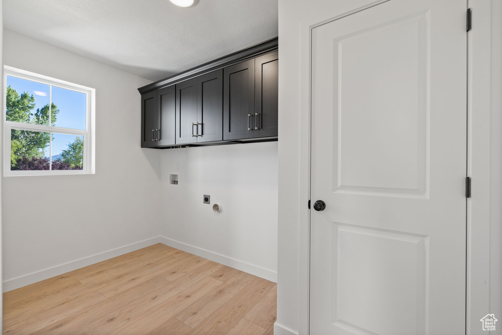 Clothes washing area featuring washer hookup, electric dryer hookup, cabinet space, baseboards, and light wood finished floors