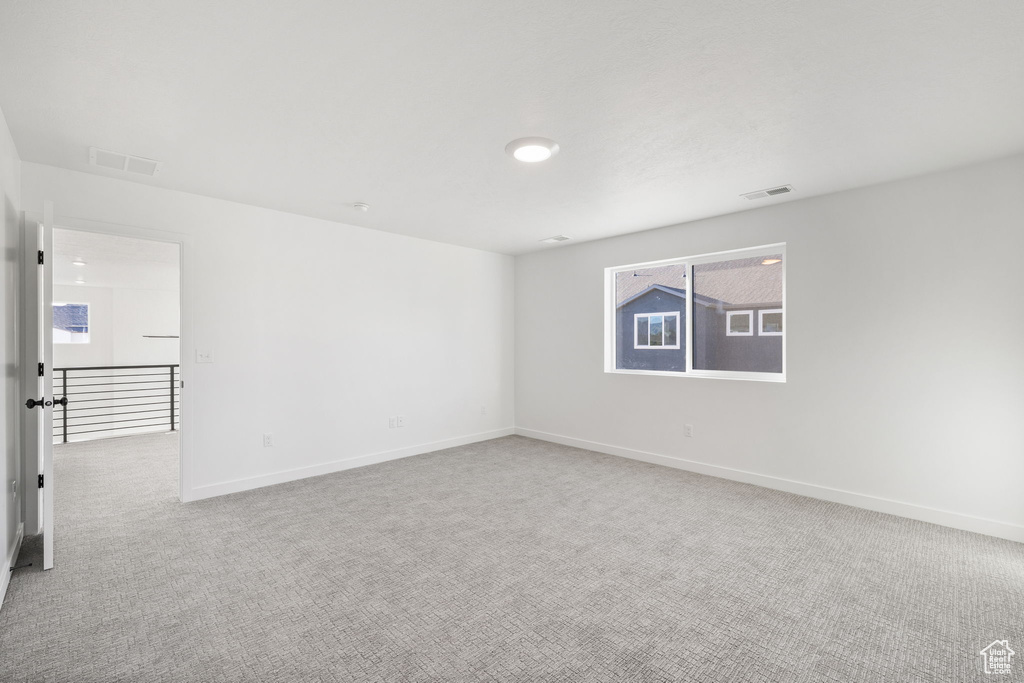 Carpeted spare room featuring baseboards and visible vents