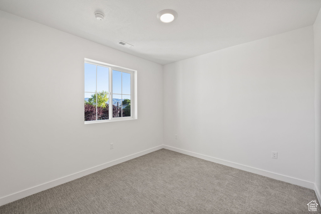 Empty room featuring baseboards, visible vents, and carpet