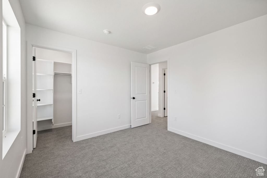 Unfurnished bedroom featuring baseboards, carpet, a closet, and a spacious closet