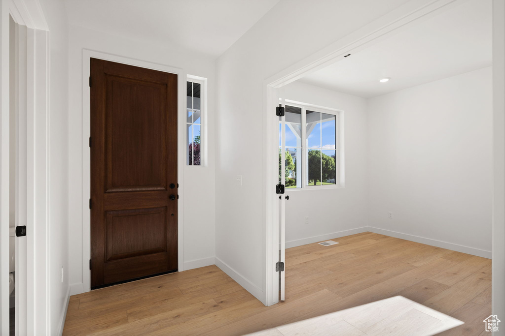 Entryway with baseboards, light wood-style flooring, and visible vents