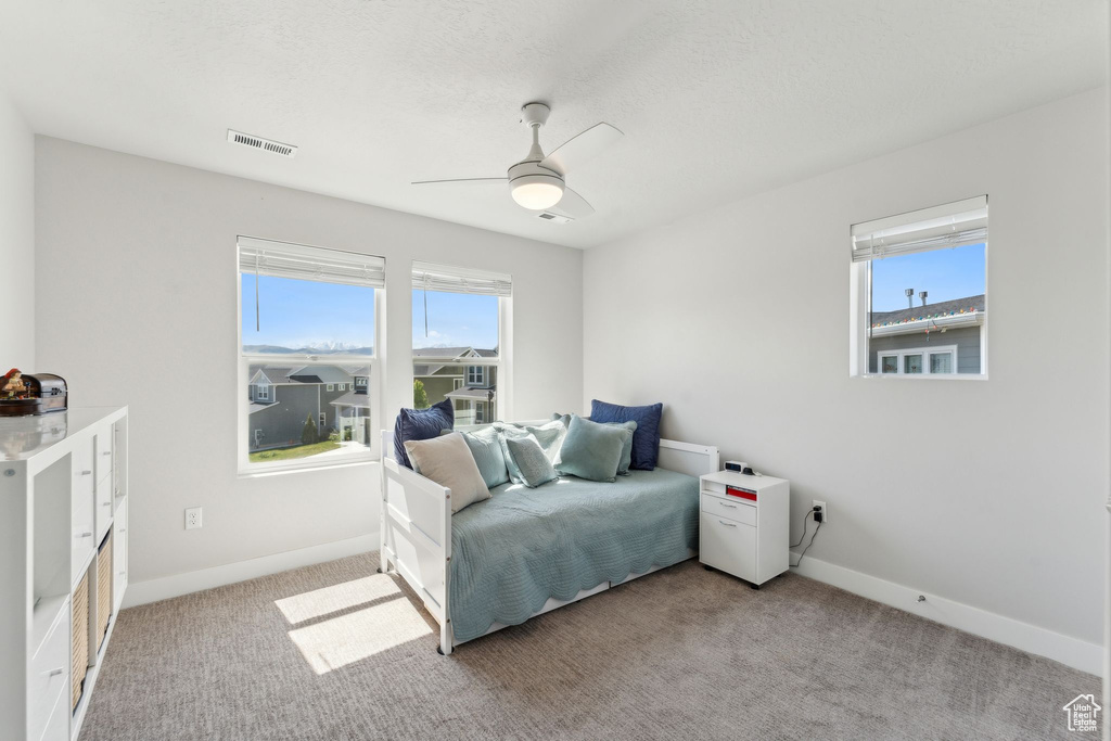 Bedroom featuring visible vents, baseboards, multiple windows, and light colored carpet