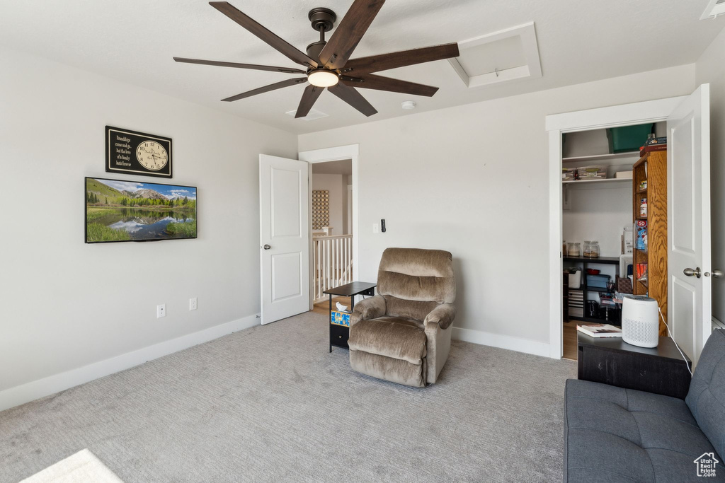 Living area with carpet floors, a ceiling fan, baseboards, and attic access