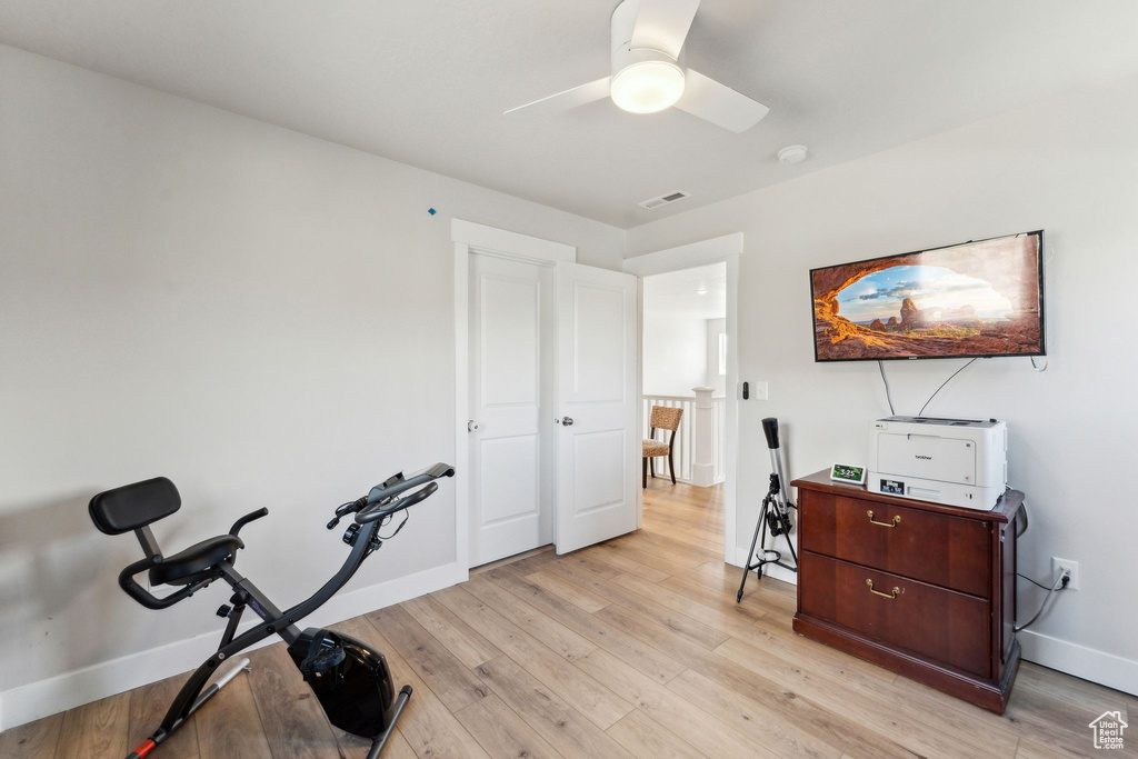 Workout area featuring a ceiling fan, baseboards, visible vents, and light wood finished floors