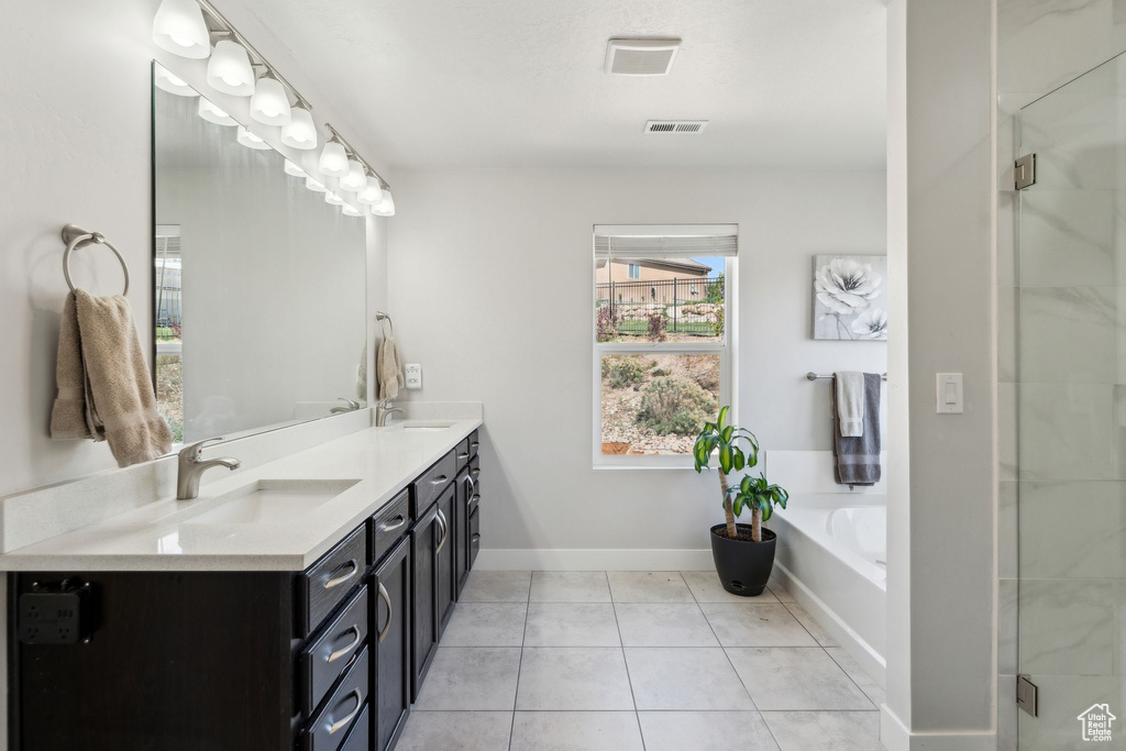 Bathroom with visible vents, tile patterned flooring, double vanity, a bath, and a sink