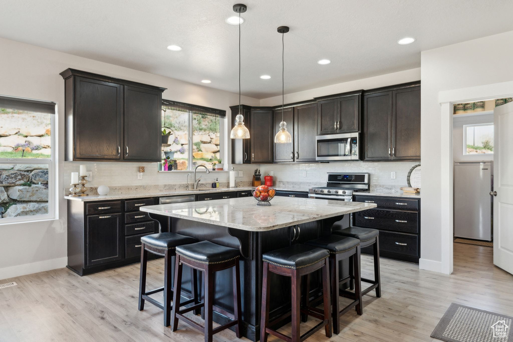 Kitchen featuring appliances with stainless steel finishes, a kitchen island, a breakfast bar, and tasteful backsplash