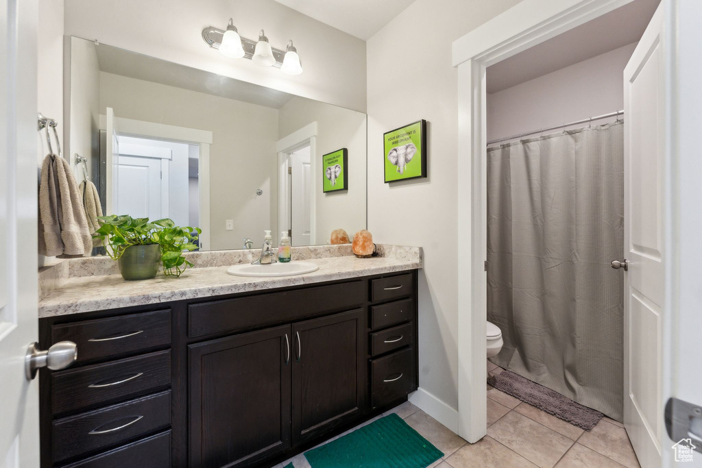 Bathroom featuring vanity, tile patterned floors, toilet, and curtained shower