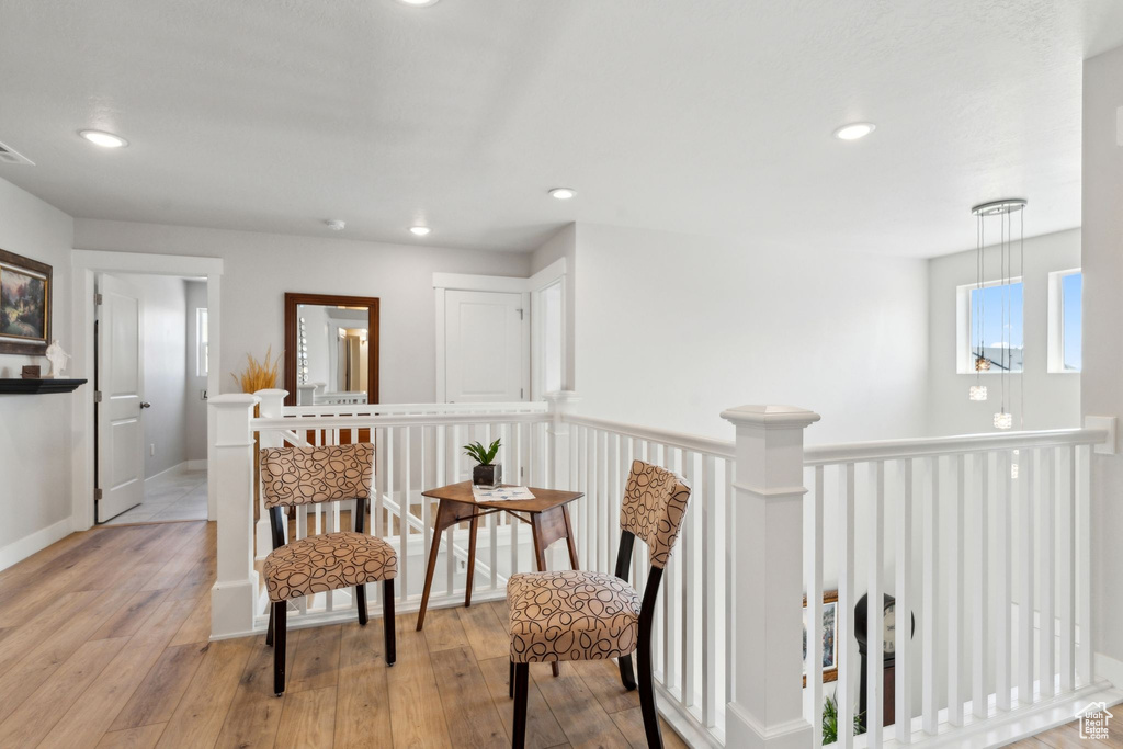 Living area with wood-type flooring, recessed lighting, visible vents, and an upstairs landing