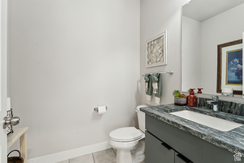 Bathroom with toilet, baseboards, tile patterned flooring, and vanity