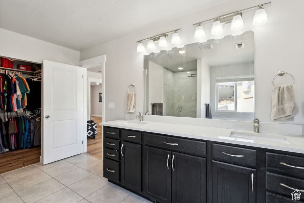 Bathroom featuring a sink, tile patterned floors, a shower stall, and double vanity