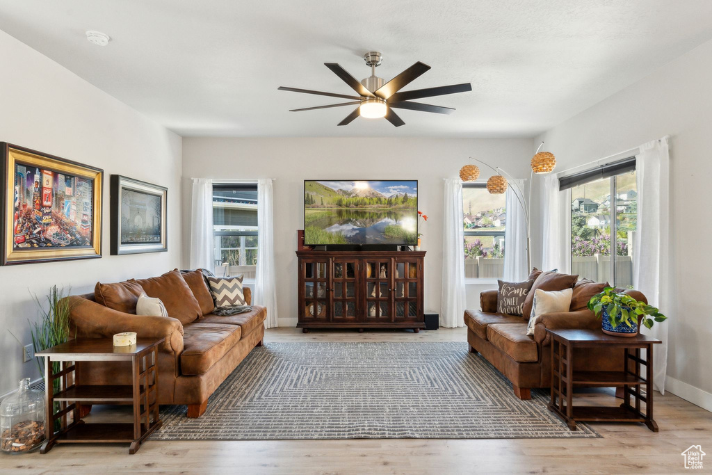 Living room featuring ceiling fan, a wealth of natural light, and wood finished floors
