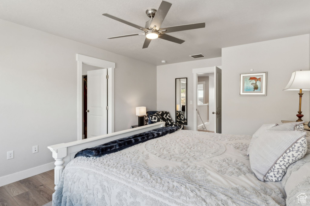 Bedroom with baseboards, ceiling fan, wood finished floors, and visible vents