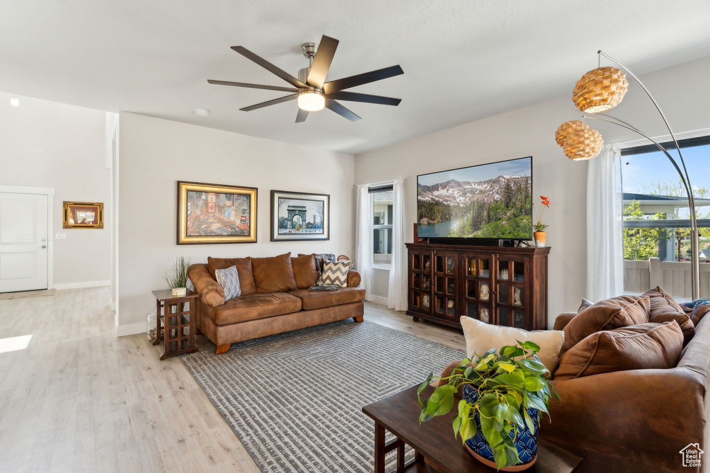 Living room with light wood-type flooring, a ceiling fan, and baseboards