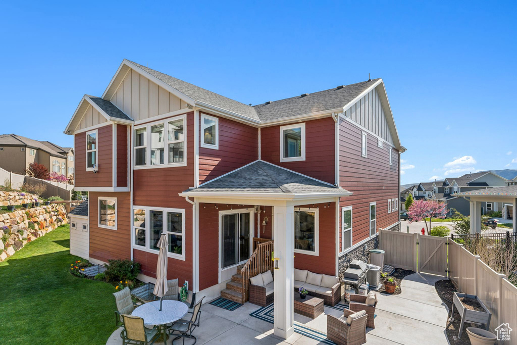 Rear view of property featuring board and batten siding, roof with shingles, a patio area, a fenced backyard, and outdoor lounge area
