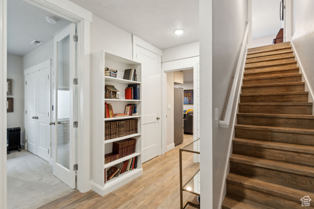 Stairs featuring visible vents, radiator heating unit, and wood finished floors