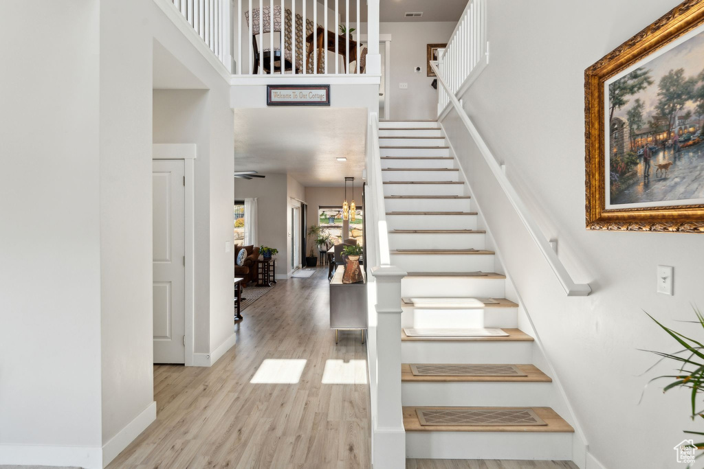 Stairs with baseboards, a high ceiling, wood finished floors, and visible vents