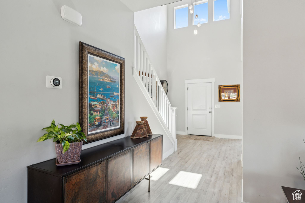 Interior space featuring baseboards, light wood-type flooring, stairs, and a towering ceiling