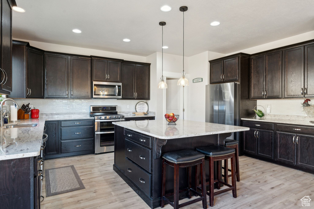 Kitchen with a sink, backsplash, stainless steel appliances, and light wood finished floors