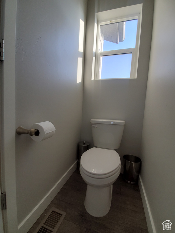 Bathroom featuring baseboards, wood finished floors, visible vents, and toilet