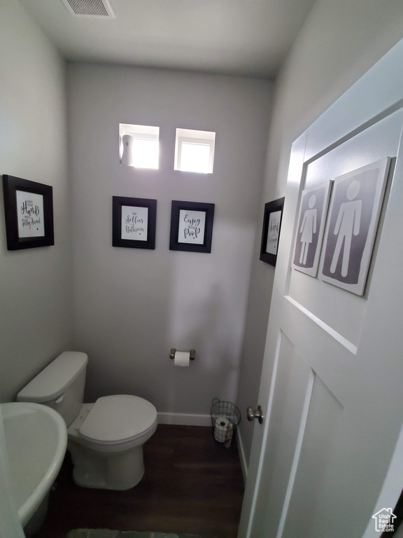 Bathroom featuring baseboards, toilet, and wood finished floors