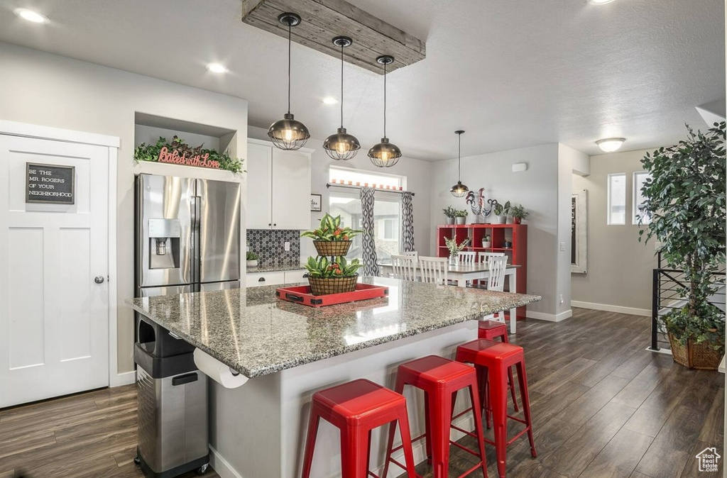 Kitchen featuring a healthy amount of sunlight, stainless steel fridge with ice dispenser, baseboards, and dark wood-type flooring