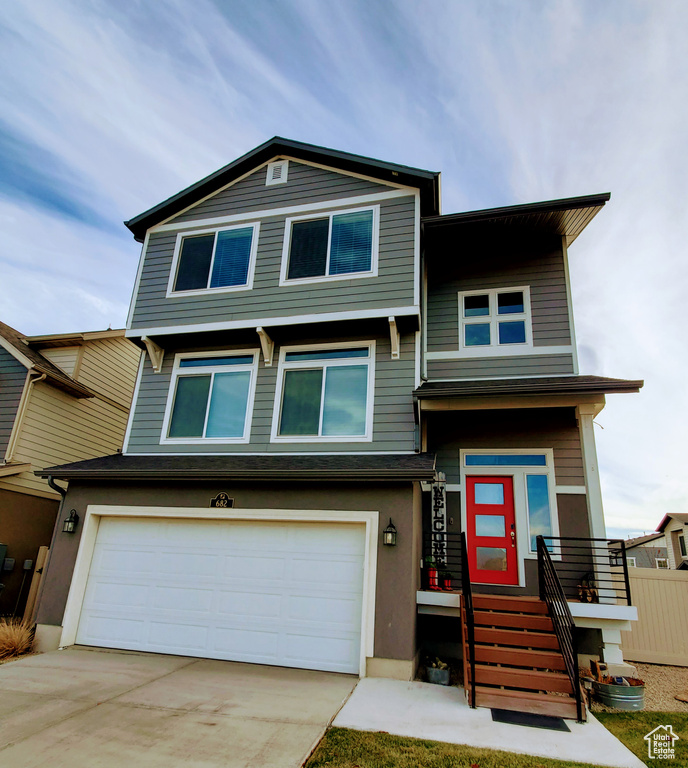 View of front of property featuring fence, an attached garage, and concrete driveway
