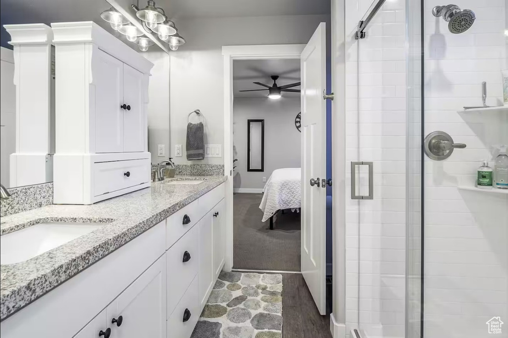 Ensuite bathroom featuring a sink, ceiling fan, ensuite bath, and a shower stall