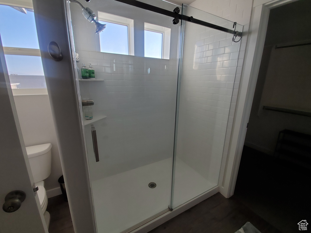 Bathroom featuring wood finished floors, toilet, and a shower stall