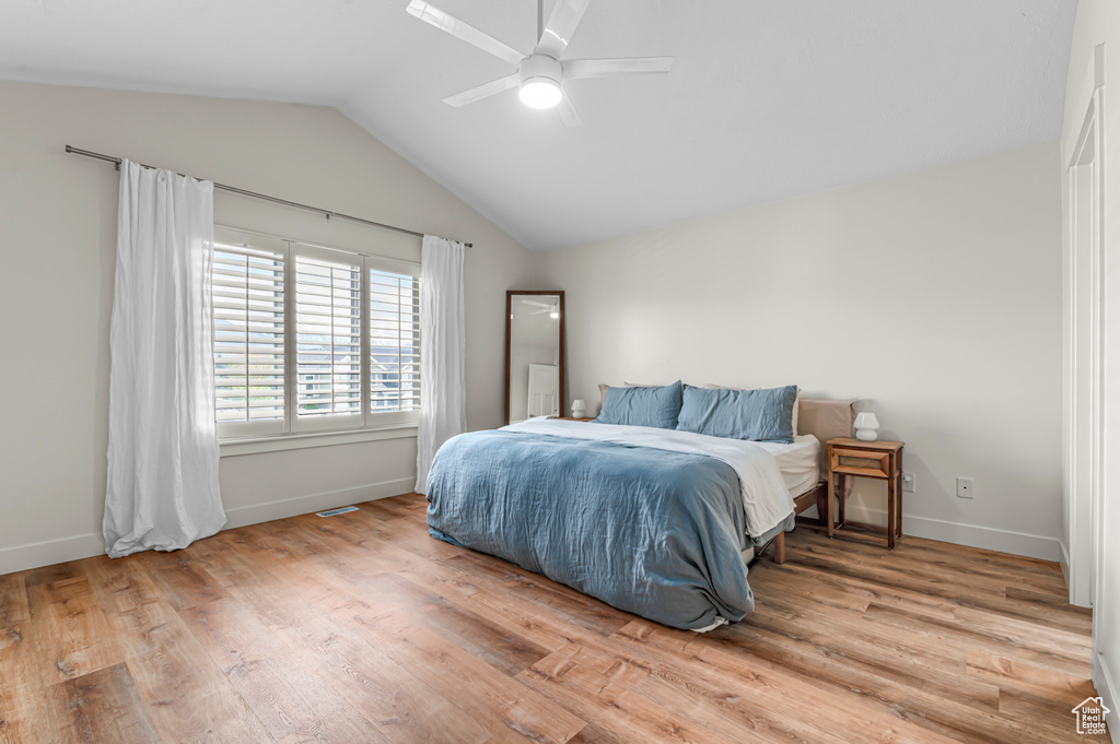 Bedroom featuring a ceiling fan, baseboards, wood finished floors, and lofted ceiling