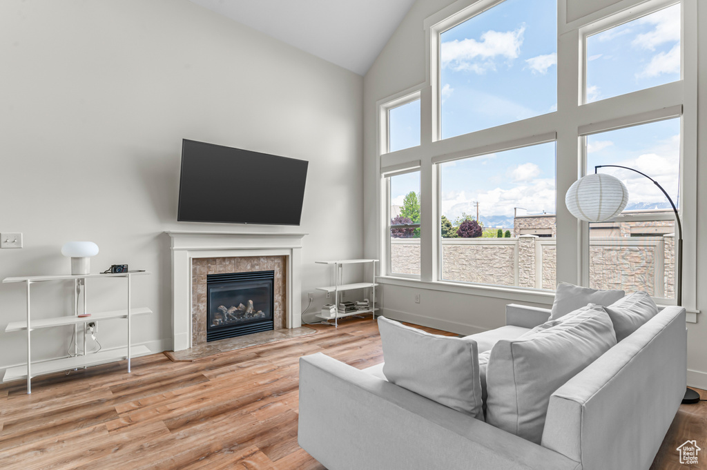 Living room with high vaulted ceiling, baseboards, wood finished floors, and a tile fireplace