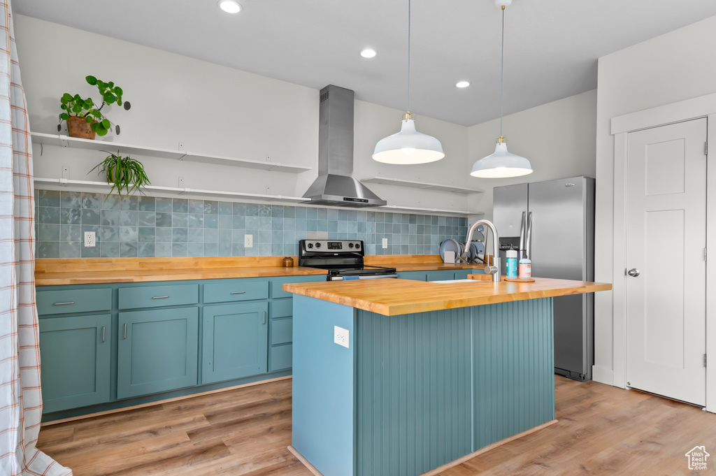 Kitchen featuring open shelves, butcher block countertops, wall chimney exhaust hood, stainless steel appliances, and light wood-type flooring