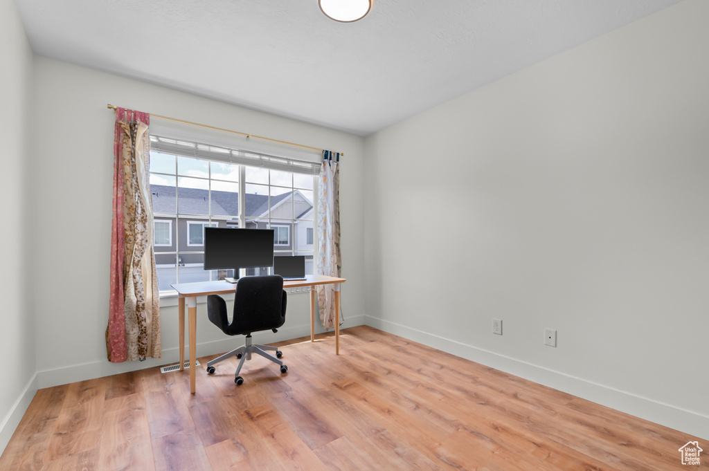 Office space featuring baseboards, wood finished floors, and visible vents