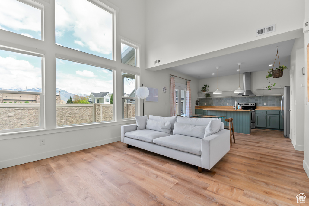 Living room featuring visible vents, a high ceiling, and light wood-type flooring