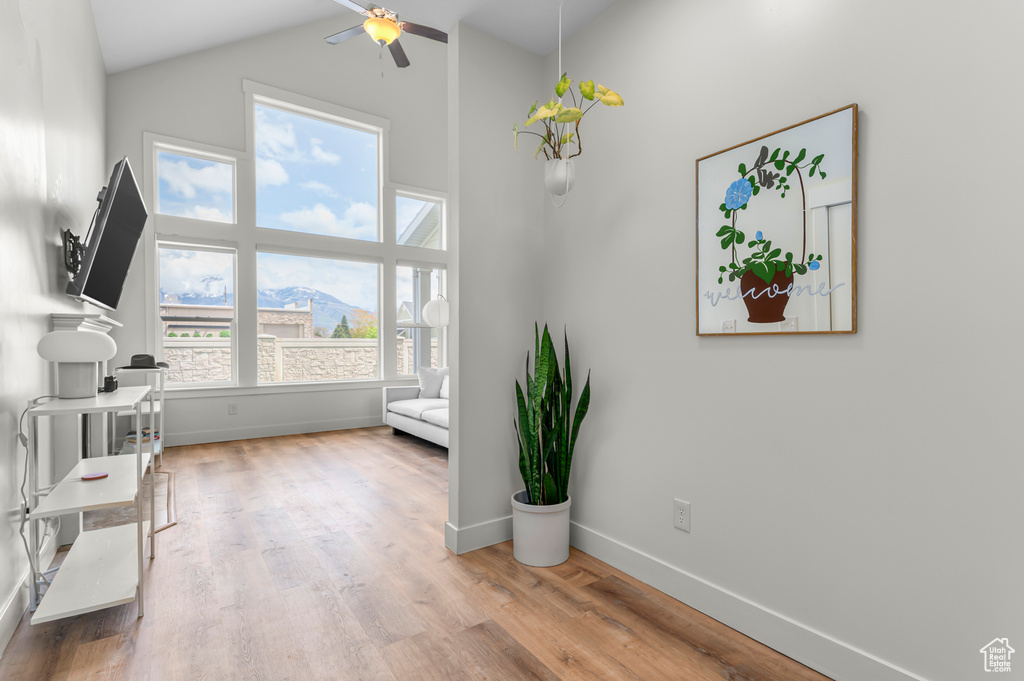 Living room with baseboards, ceiling fan, wood finished floors, and high vaulted ceiling