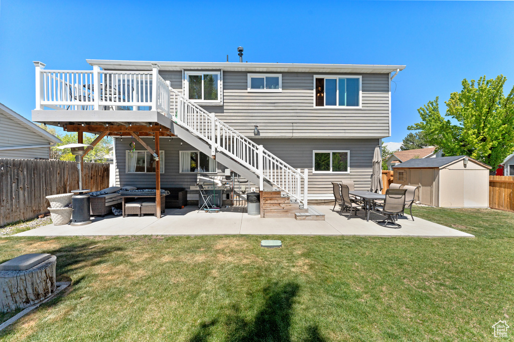 Back of property with an outdoor living space, a storage shed, a deck, an outdoor structure, and a fenced backyard