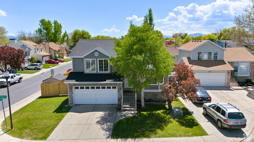 View of front facade with a garage, a front lawn, a residential view, and concrete driveway