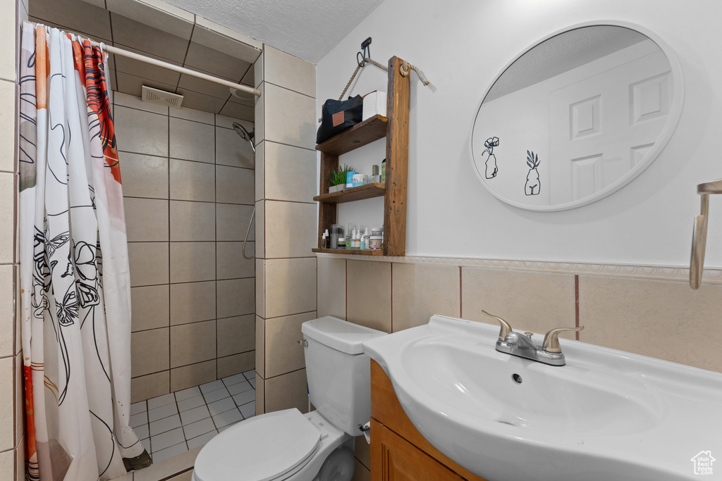 Full bathroom with vanity, tile walls, toilet, and tiled shower