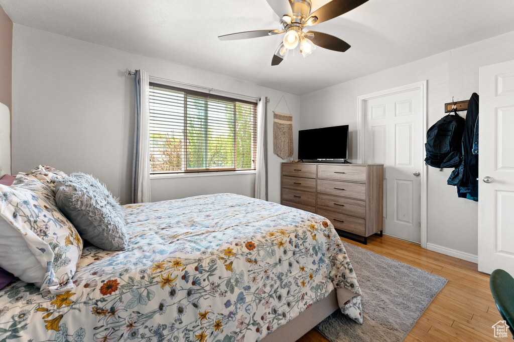 Bedroom with a ceiling fan, baseboards, and light wood-type flooring