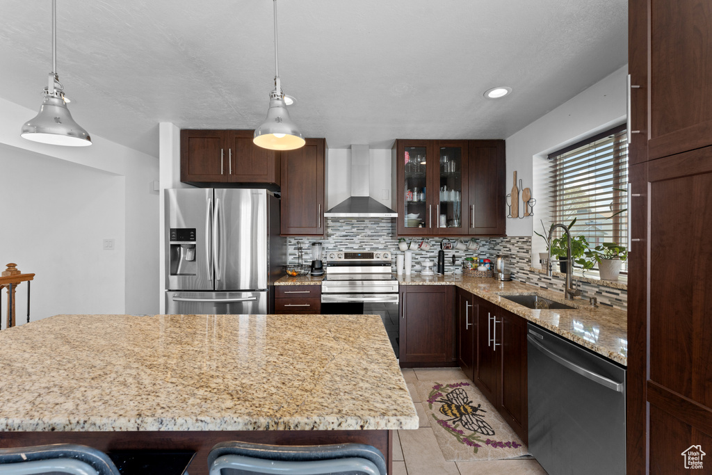 Kitchen featuring a sink, appliances with stainless steel finishes, decorative backsplash, and wall chimney exhaust hood
