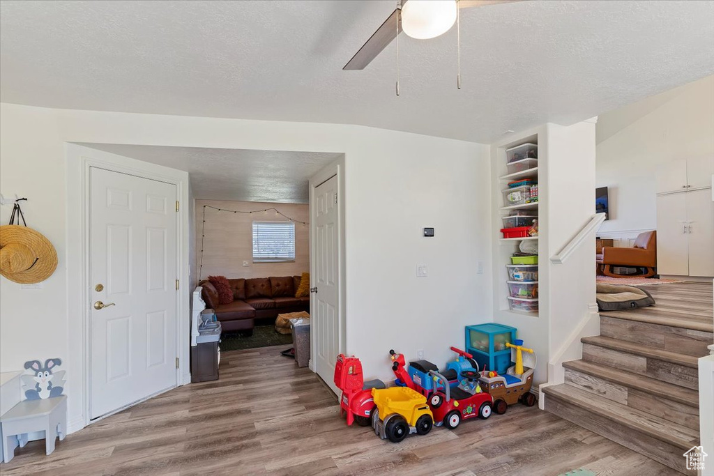 Game room with a ceiling fan, a textured ceiling, and wood finished floors