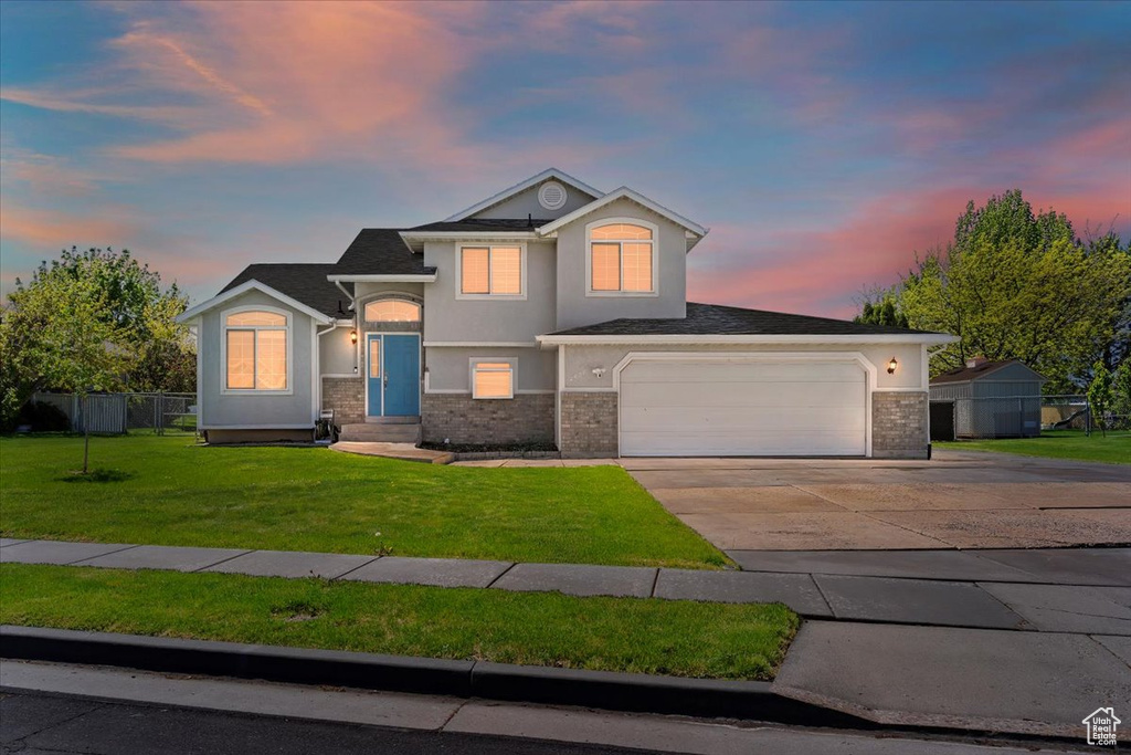 View of front of property featuring fence, brick siding, stucco siding, a front yard, and driveway