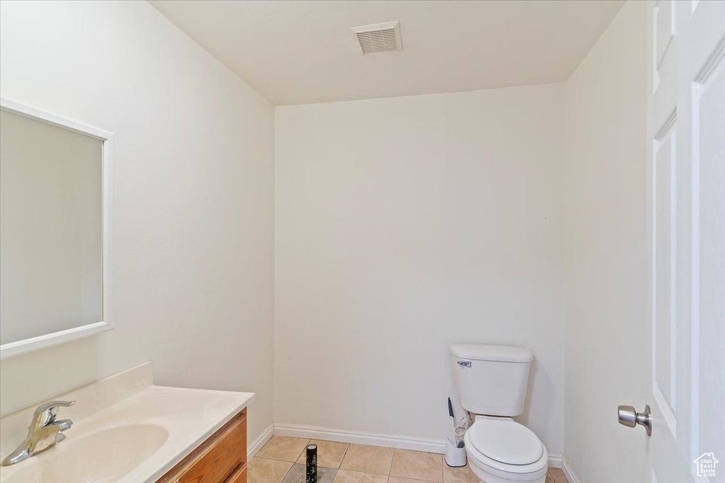 Half bathroom with visible vents, vanity, toilet, baseboards, and tile patterned floors