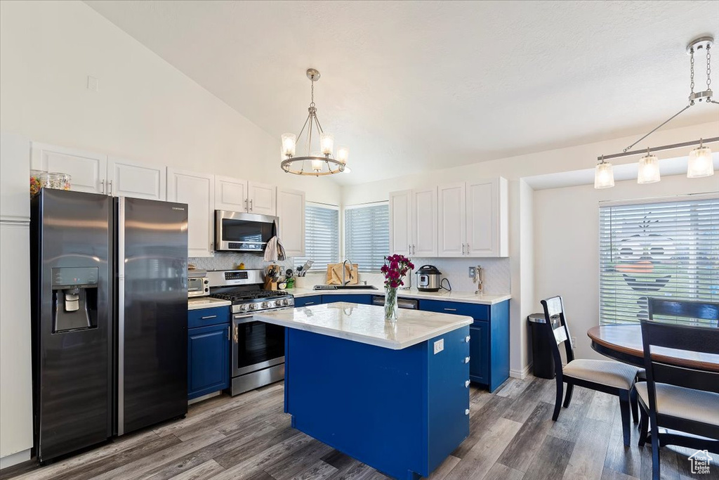 Kitchen with blue cabinets, appliances with stainless steel finishes, backsplash, and a notable chandelier