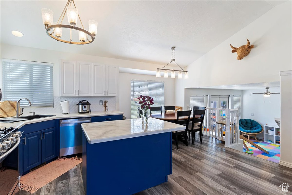 Kitchen featuring appliances with stainless steel finishes, a sink, light countertops, blue cabinetry, and vaulted ceiling