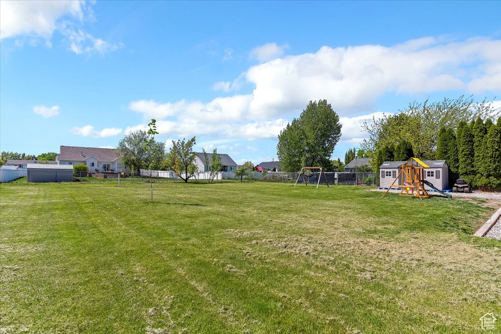 View of yard featuring fence, an outbuilding, a playground, and a storage unit